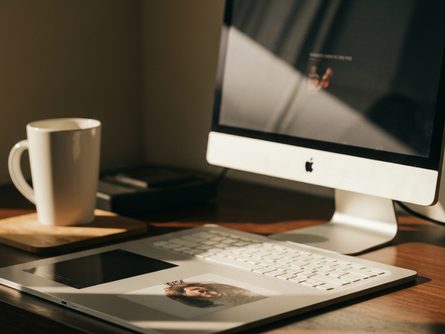 책과 노트가 놓인 나무 책상 위에 독서용 안경과 연필이 함께 배치된 학습 환경