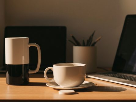 흰색 노트북 앞에 펼쳐진 서류와 펜, 손으로 잡은 신용카드 클로즈업, 밝은 실내 배경